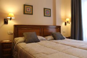 a bedroom with two beds and two lamps on the wall at Apartamentos La Lula in Cudillero