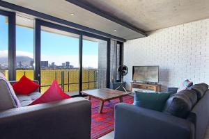 Sala de estar con 2 sofás, mesa y TV en Wex apartments, en Ciudad del Cabo
