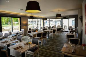 a restaurant with wooden tables and chairs and windows at Logis La Lentillere - Restaurant Côté Parc in Lalacelle