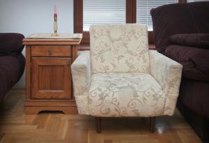 una silla sentada en una sala de estar junto a una mesa en Mladenovic apartments en Kladovo