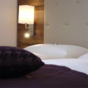 a bedroom with a bed with a lamp and a pillow at Hotel Feichtinger Graz in Graz