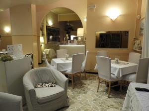 ボルゲット・サント・スピーリトにあるAlbergo Gloryの白いテーブルと椅子、鏡のあるレストラン