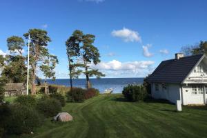 ein Haus auf einem Rasen neben dem Wasser in der Unterkunft Sea Breeze Cottage in Eisma