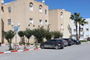 un estacionamiento con autos estacionados frente a un edificio en Apartment Tunis 1 Near airport en Ariana