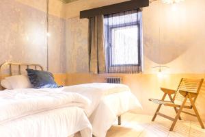 a bedroom with two beds and a chair and a window at Casa Rural La Abacería in Mino de Medinaceli