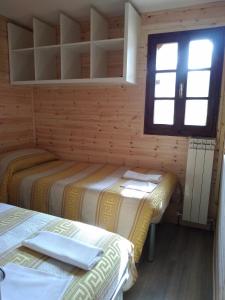 2 letti in una piccola camera con finestra di Camping Pineta a Calambrone