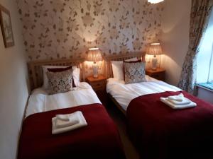 two beds in a room with two lamps and towels at The Black Bull at Nateby in Kirkby Stephen