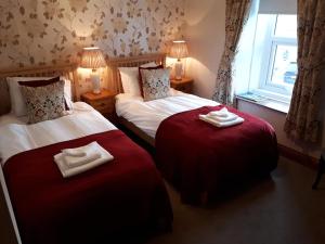 two beds in a hotel room with towels on them at The Black Bull at Nateby in Kirkby Stephen