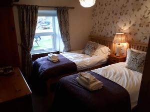 a hotel room with two beds and a window at The Black Bull at Nateby in Kirkby Stephen