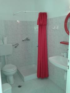 ein Badezimmer mit Toilette und rotem Duschvorhang in der Unterkunft Balaska House in Region Ilia