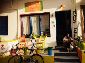 um homem sentado à porta de um edifício com um cão em Viva Margarita em Parikia