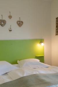 a bedroom with a white bed with a green wall at Gîte l'Agapé in Riquewihr