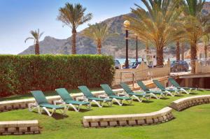 a row of lawn chairs sitting in the grass at KAKTUS Hotel Kaktus Albir in Albir