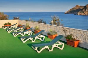a row of chaise lounges on a patio with the ocean at KAKTUS Hotel Kaktus Albir in Albir