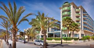 a building with palm trees in front of a street at KAKTUS Hotel Kaktus Albir in Albir