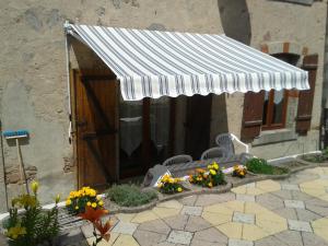 eine weiße Markise über einer Terrasse mit Blumen in der Unterkunft la maison seillere in Senones