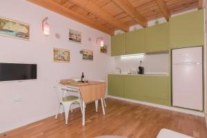 una cocina con armarios verdes, mesa y sillas en Rose Green Loft, en Oporto