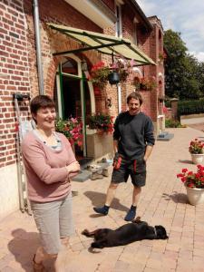 un hombre y una mujer de pie junto a un perro en Au gîte du treuil, en Monchy-au-Bois