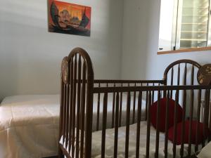 サン・ペドロ・デル・ピナタルにあるTuAlbergueJTのベッドルームに赤い椅子が備わるベビーベッド