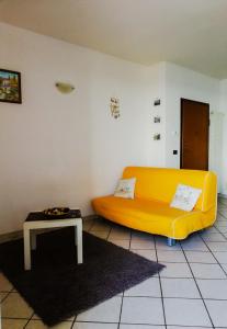 un sofá amarillo en una sala de estar con mesa en A Cà d'Assunta, en Laigueglia 5 fotos más