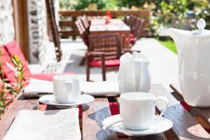 een tafel met twee witte bekers en een vaas erop bij Chambres d'hôtes La Grangelitte in Doussard