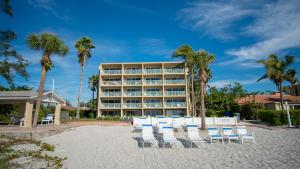 a hotel with chairs and palm trees on a beach at Amazing Panoramic Beach View and The Most Beautiful Sunset in Longboat Key