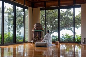 a person sitting in front of a fireplace in a room with windows at Vida Mountain Resort & Spa Adults Only in San Ramón