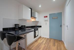 a kitchen with white cabinets and a black counter top at Victoria House Apartments in Leeds