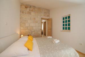 a bedroom with a bed with yellow and white pillows at Vacation house "Kaštil" Pučišća - Brač in Pučišća