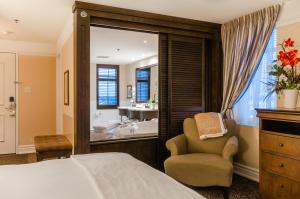 a bedroom with a bed and a chair and a tub at Le St-Martin Hotel & Suites in Laval +37 photos