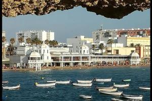a group of boats in the water in front of a city at La Casa del Arte in Cádiz