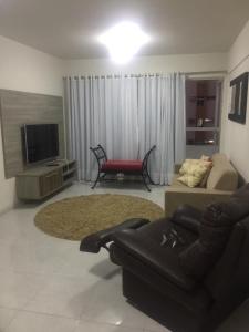 ein Wohnzimmer mit einem Sofa und einem TV in der Unterkunft Apartamento 3 quartos em frente ao Mar in Recife