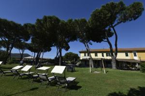 a group of tables and chairs in a field with trees at Agriturismo Redipuglia in Alberese