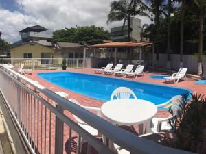 un balcón con mesa y sillas junto a una piscina en KIT 5 - Estúdio com churrasqueira piscina ar wifI vaga cozinha, en Itapema