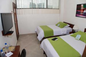 a room with two beds and a flat screen tv at Hotel Castell - Cerca Del Aeropuerto in Guayaquil