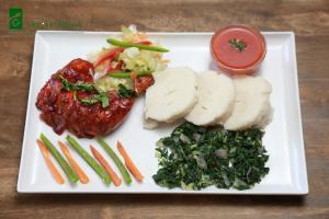 a plate of food with meat and vegetables and a sauce at Hotel Embassy in Nairobi
