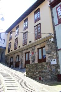 ein Steingebäude mit braunen Türen und Fenstern in der Unterkunft Apartamentos La Lula in Cudillero