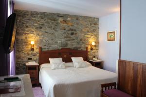 a bedroom with a bed and a stone wall at Hotel Casa Prendes in Cudillero