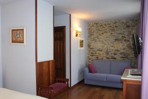 a bedroom with a blue couch and a stone wall at Hotel Casa Prendes in Cudillero
