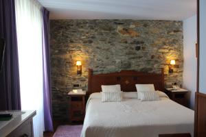 a bedroom with a bed and a stone wall at Hotel Casa Prendes in Cudillero