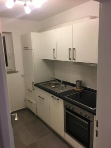 a kitchen with white cabinets and a sink and a stove at Ferienwohnung Tettnang in Tettnang
