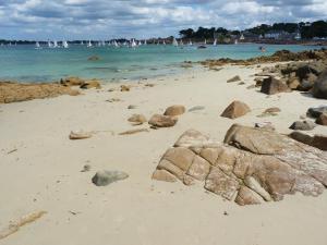 a beach with rocks and the water and boats at Les crèches de Boiséon in Penvénan