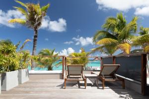 a balcony with two chairs and the ocean at Pearl Beach Hotel in Gustavia