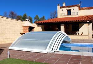 a swimming pool with a retractable shade next to a house at Casa rural Laguna de Uña in Uña