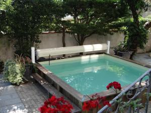 - une piscine avec un banc et des fleurs dans l'établissement Chambres d'hôtes Le Clos Bleu, à La Rochelle
