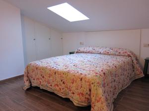 1 dormitorio con 1 cama grande con colcha de flores en EL CHORRO DE JERTE, en Jerte