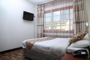 a bedroom with a bed and a large window at Hotel Embassy in Nairobi