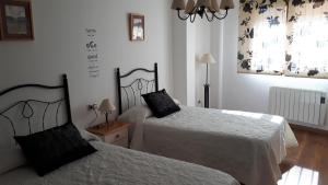a bedroom with two beds with white sheets at Casa Tere in Orihuela del Tremedal