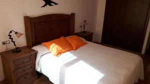 a bedroom with a bed with an orange pillow at Casa Tere in Orihuela del Tremedal +4 photos
