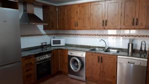 a kitchen with wooden cabinets and a washer and dryer at Casa Tere in Orihuela del Tremedal